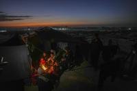 Reda Abu Zarada, 50, displaced from Jabaliya in northern Gaza, sits by a fire with her grandchildren