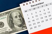 Situated diagonally, a US $100 bill takes up about the left half of the frame, while a generic month of the December calendar page takes up the right half.