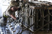 Airmen push over 8,000 pounds of 155 mm shells ultimately bound for Ukraine onto a C-17 aircraft