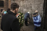 Survivors and relatives place candles near the Death Wall during a ceremony