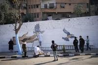 Volunteers paint a mural symbolizing peace on a wall in Damascus, Syria.