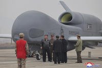 Kim Jong Un, center left in a black jacket, stands by what appeared to be a large reconnaissance drone
