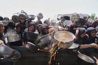 Palestinians struggle to get donated food at a community kitchen in Khan Younis, Gaza Strip