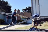 Movers load a service member’s household goods into a moving truck at a residence