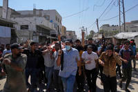 Palestinians, some armed, carry the body of Farouq Khattab, 29, who was killed in an Israeli army airstrike
