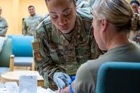 Official in military uniform administers a shot.