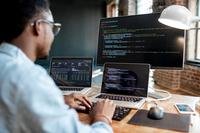 Computer programmer works at an array of screens.