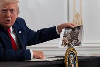 President Donald Trump holds up a photograph.