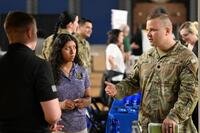 A National Guard members talks to two people at a job fair.