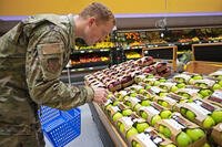 A U.S. Air Force Airman selects produce while grocery shopping at Ramstein Air Base, Germany, May 17 2022. (Thomas Karol)