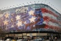 A billboard depicting a damaged U.S. aircraft carrier with disabled fighter jets on its deck.
