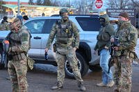 Federal agents stand outside the Bishop Henry Whipple Federal Building as protesters gather in Minneapolis, Friday, Jan. 9, 2026. (AP Photo/Adam Bettcher)