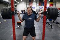 A senior Army general wearing PT gear lifts weights.