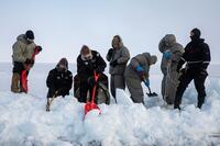 Sailors in snow suits shovel deep snow.