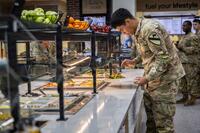 A soldier gets food at a buffet.