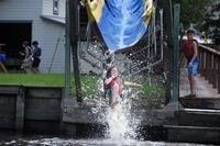 A child splashes into a lake from a water slide.