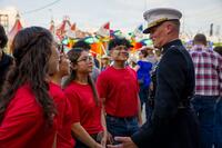 Young Marine recruits in red T-shirts talk to a general in a dress uniform.