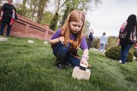 A child brushes off a cemetery marker.