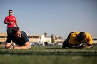 Sailors do plank pose side by side in the grass.