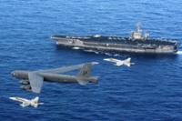An Air Force B-52 Stratofortress flies past the Navy aircraft carrier USS Nimitz, escorted by two Navy F/A-18 Hornets.  A B-52 recently flew over contested territory in the South China Sea. (U.S. Navy photo)