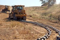 A V8T Dozer drags a chain across a firebreak to flatten its surface as another dozer clears brush from the path, aboard Camp Pendleton, Calif., May 13, 2014.