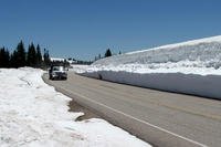 Truck driving on a road flanked by snow.