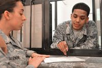 Air Force Senior Airman Jon-Nicos Walker, a military pay technician, helps a customer fill out financial paperwork at Contingency Operating Site Marez near Mosul, Iraq, on April 12, 2011. U.S. Air Force photo by Senior Airman Andrew Lee