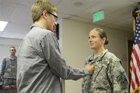 Staff Sgt. Cristina Cost's son, Zach, puts on her new rank during her promotion ceremony. (U.S. Army/ Staff Sgt. Benjamin Crane)
