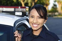 A young police officer standing next to her car.