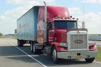 Red semi truck hauling cargo on the road.