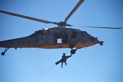 Pararescueman is hoisted up to a U.S. Navy MH-60 Seahawk.