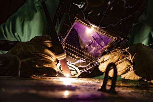 A U.S Navy technician welds a watertight door for shipboard use.