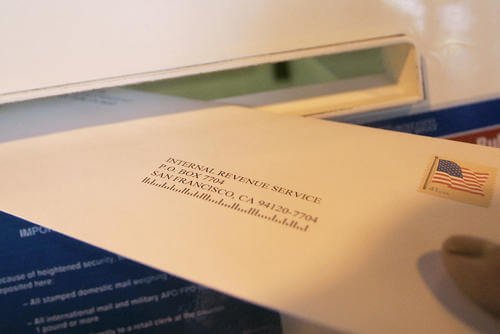 A woman drops her federal tax return in a mail slot at a post office in Palo Alto, California.