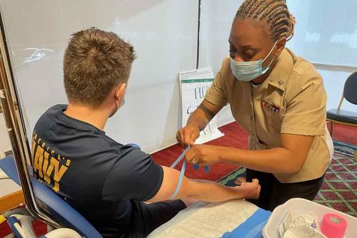 Medical technician prepares to draw blood from a sailor
