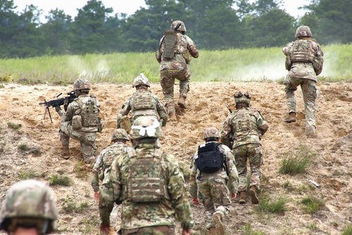 U.S. Army fire teams head over the bunker during a squad live fire assault mission